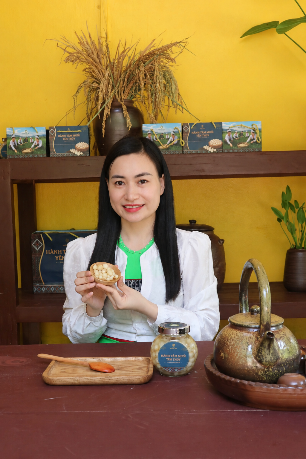 Người phụ nữ Mường Việt cầm chén hành tăm muối bên hũ sản phẩm